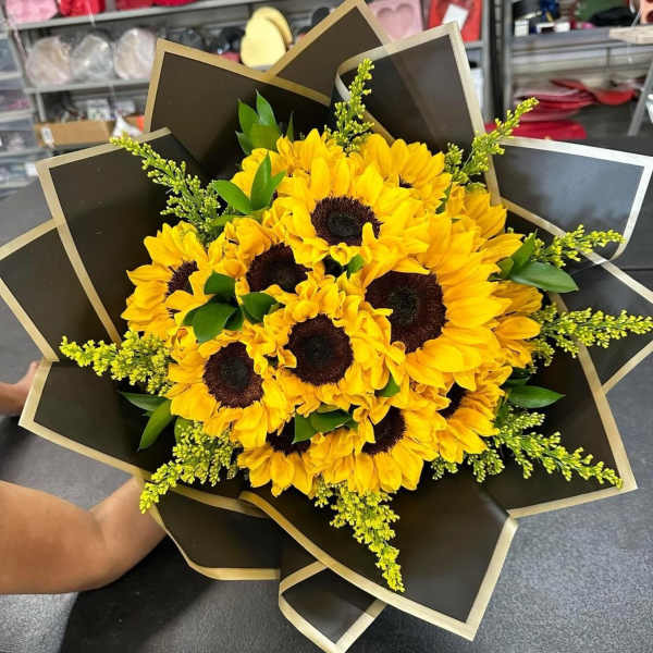 Bouquet of yellow sunflowers wrapped in black paper with gold trim