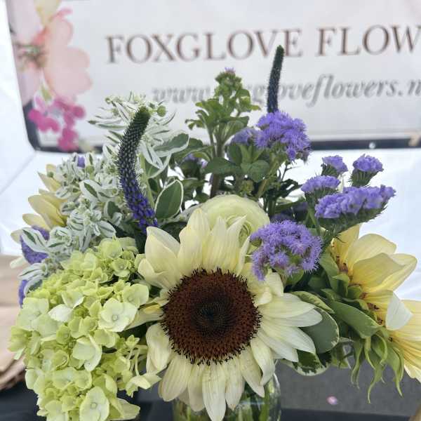 Sunflower and hydrangea bouquet in a glass vase with purple accents