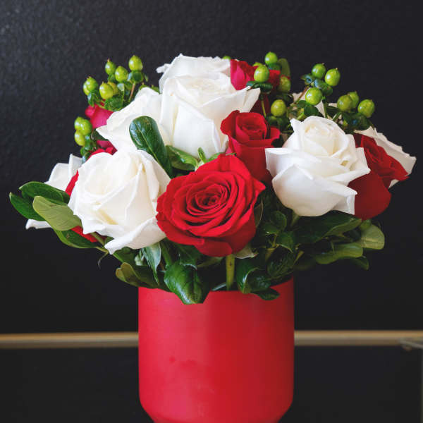 Red and white roses arranged in a red vase