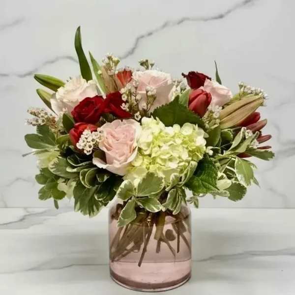 Mixed roses and hydrangea in a pink glass vase
