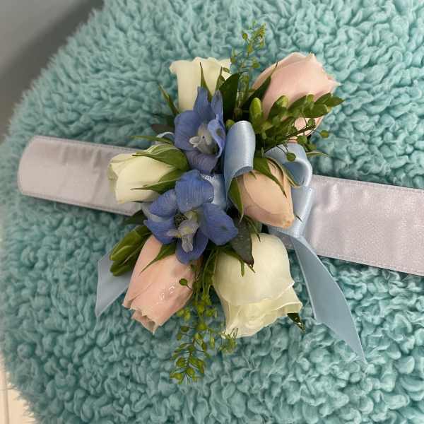 Corsage with pastel roses and blue flowers on a satin wristband