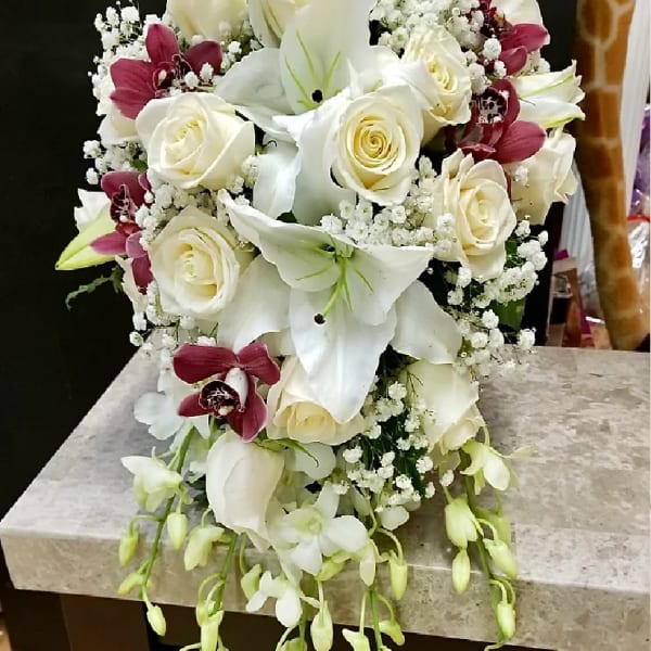 White roses and lilies with burgundy orchids in a compact bouquet