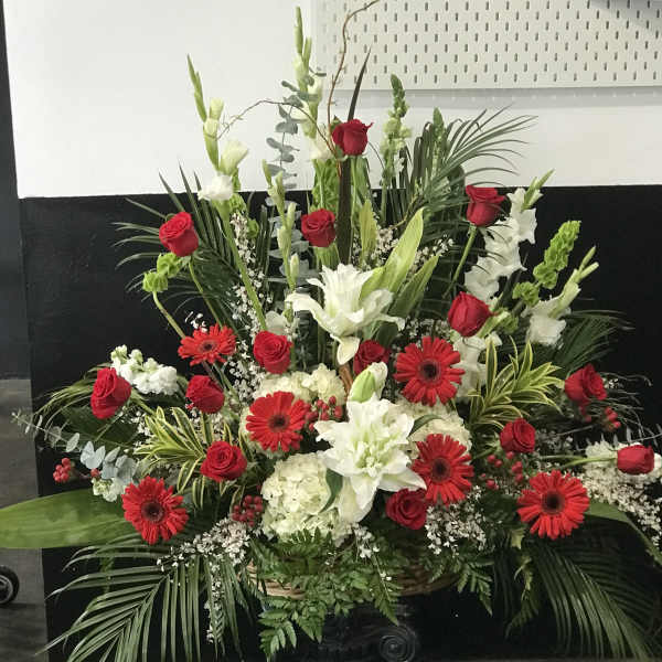 Large red and white floral arrangement in a black pedestal vase