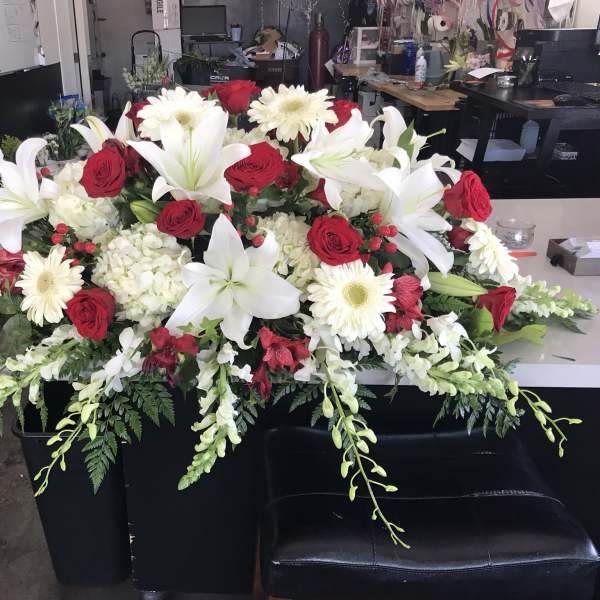 Large floral casket spray with white lilies, red roses, and white daisies