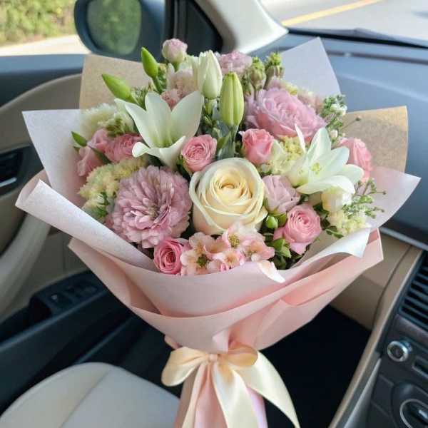 Pink and white mixed bouquet wrapped in pastel paper with a ribbon