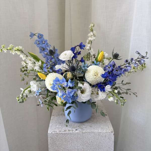 Blue and white floral arrangement in a light blue vase