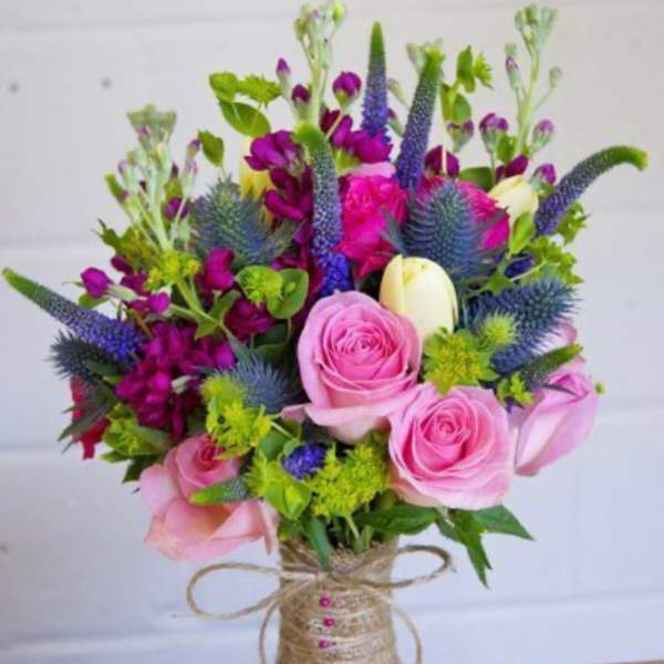 Bouquet of pink roses and purple flowers wrapped with twine