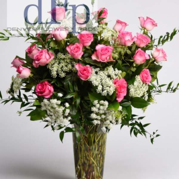 Pink roses and white filler flowers in a clear glass vase