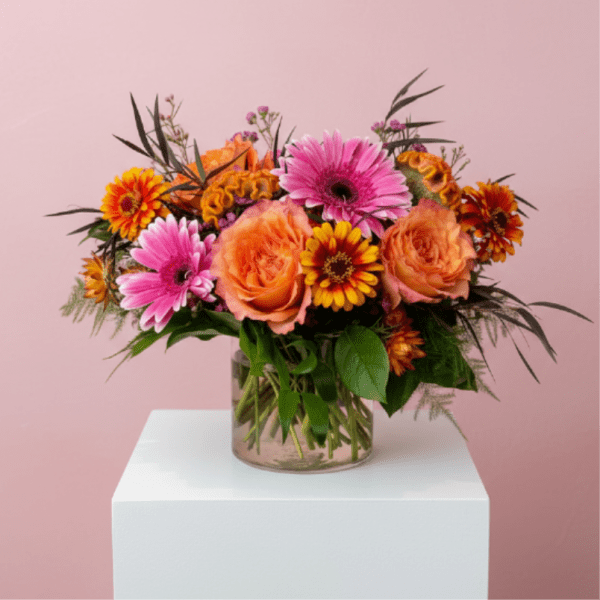 Mixed bouquet of orange and pink flowers in a clear glass vase