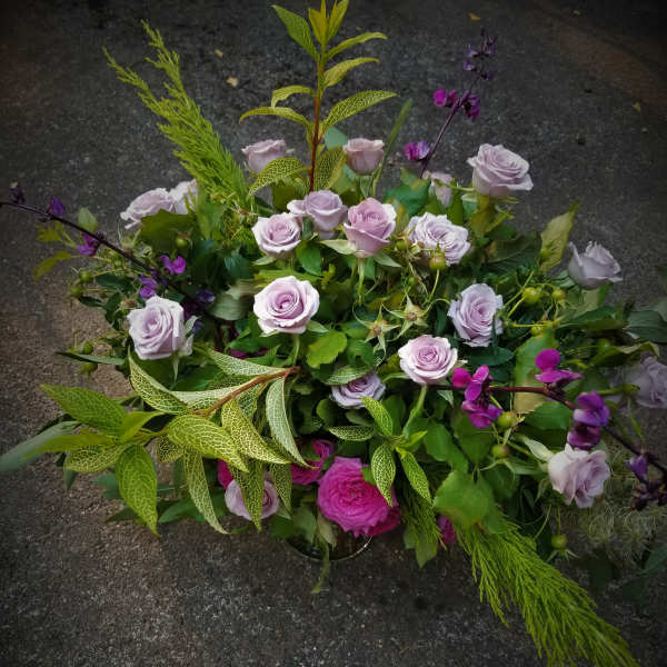 Low garden-style arrangement of lavender roses with bright pink accents and airy greenery
