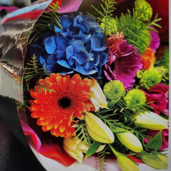 Colorful bouquet with blue hydrangea, orange gerbera daisy, and yellow tulips