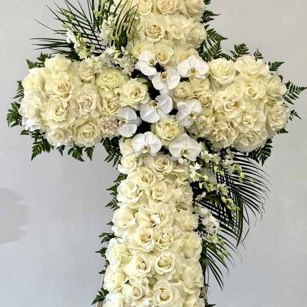 Cross-shaped floral spray of white roses and orchids on an easel