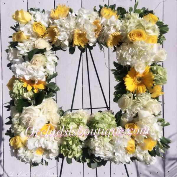 Square floral wreath with white and yellow flowers on a black stand