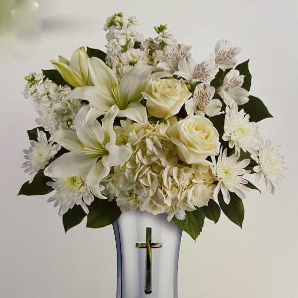 White floral arrangement in a silver vase with a cross