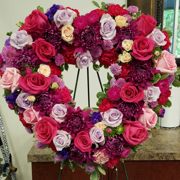 Heart-shaped standing wreath of pink and purple roses and chrysanthemums on an easel