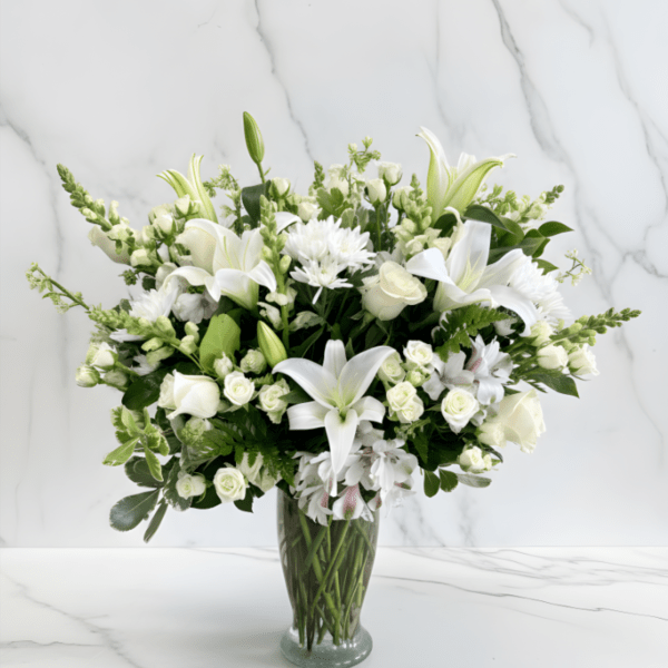 White lilies and roses arranged in a clear glass vase
