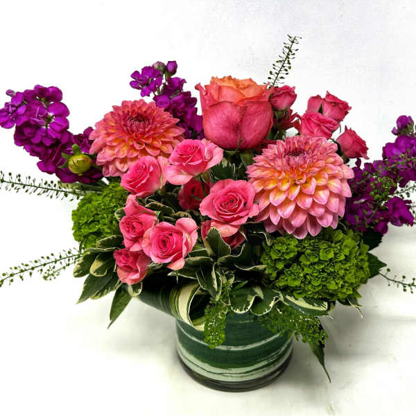 Pink and purple flower arrangement in a green striped vase