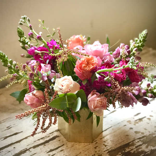 Pink and coral roses arranged in a gold vase