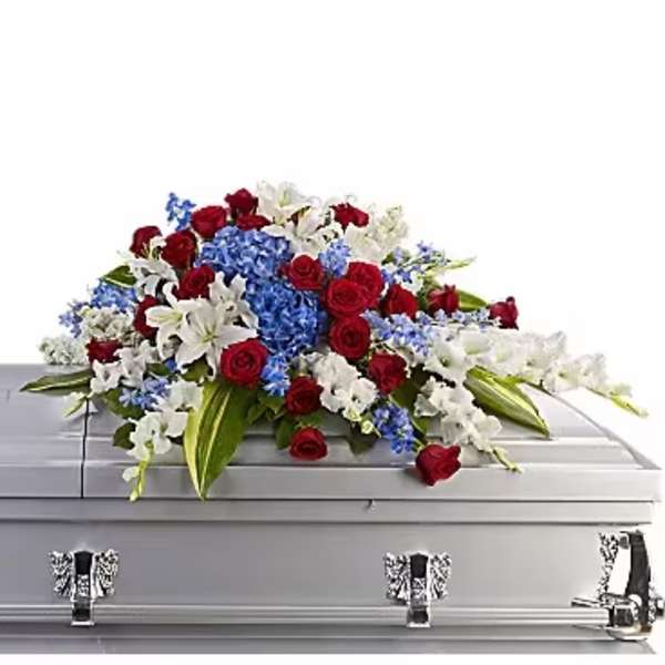Red roses, white lilies, and blue flowers arranged on a silver casket