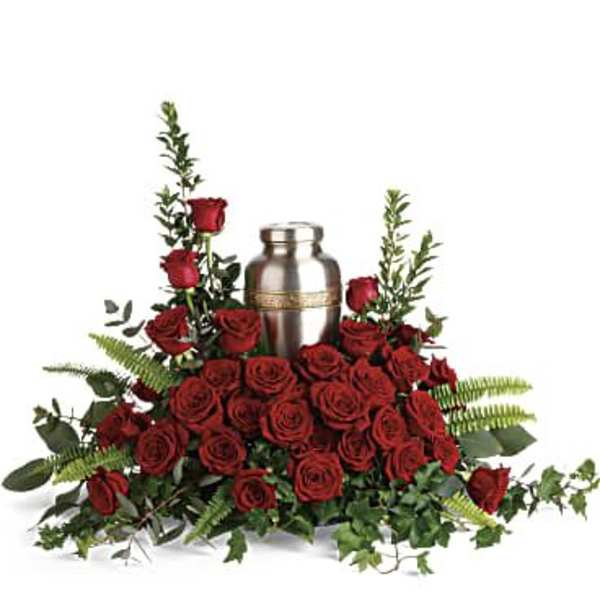 Red roses arranged around a silver urn with greenery
