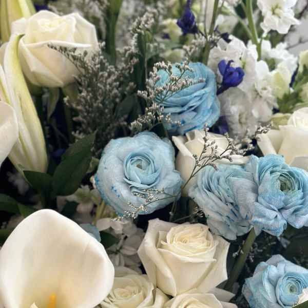 Bouquet of white roses, blue ranunculus, and white calla lilies