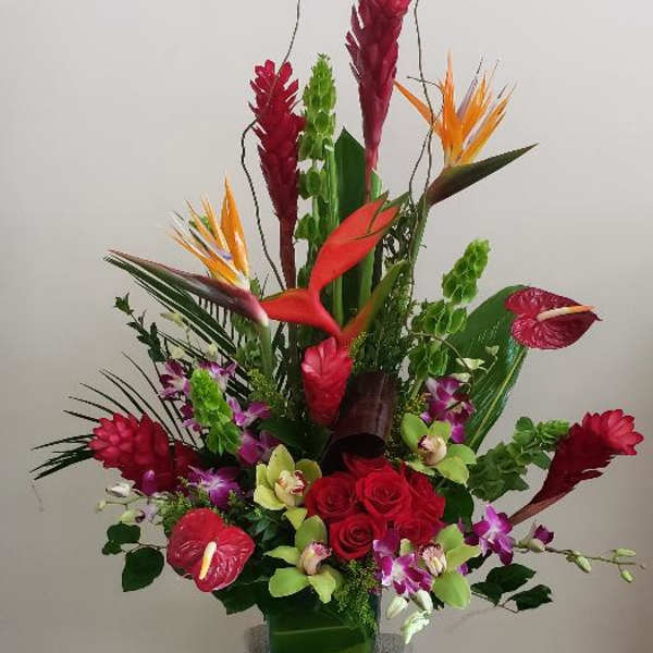 Tall tropical flower arrangement in a decorative pedestal vase