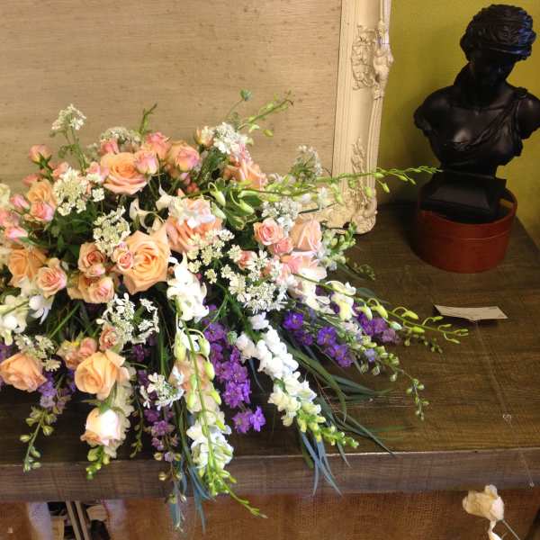 Low floral arrangement with peach roses, white blooms, and purple flowers