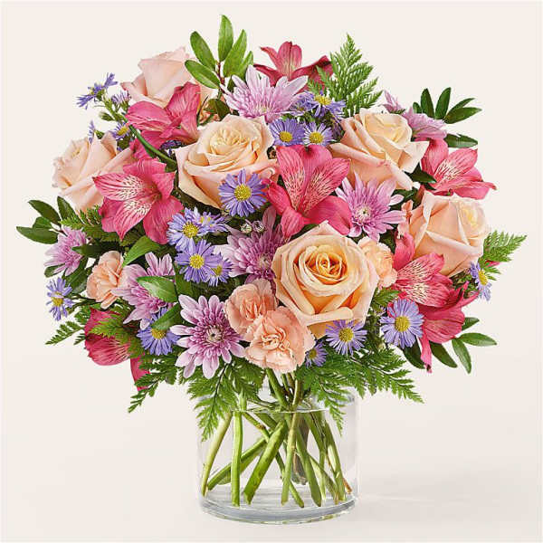 Bouquet of peach roses, pink lilies, and purple daisies in a glass vase