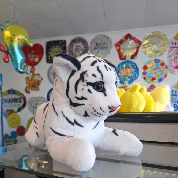 White plush tiger toy with black stripes on a counter