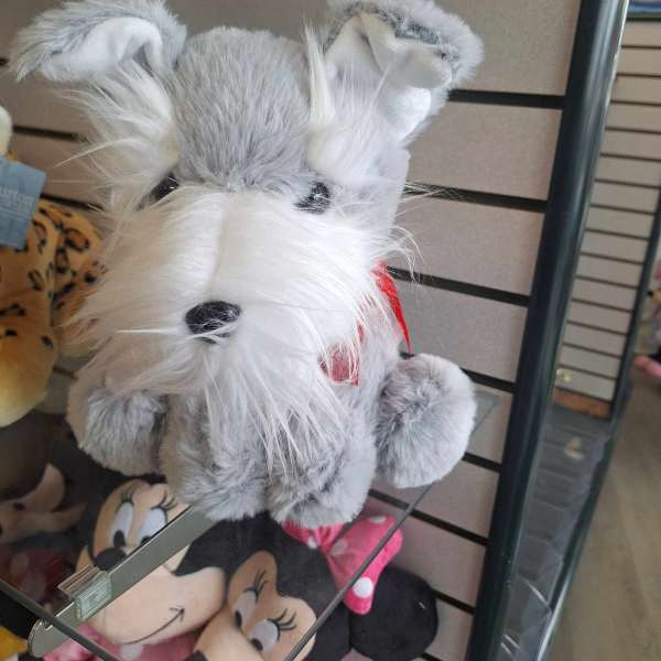 Gray and white plush dog toy with a red scarf on a store shelf