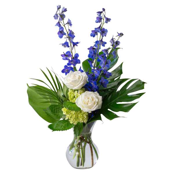 Blue delphinium and white roses in a clear glass vase