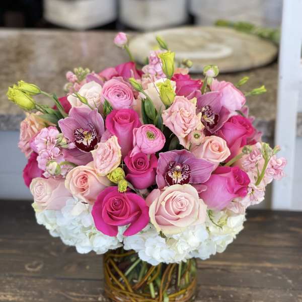 Pink and white rose bouquet with orchids in a glass vase