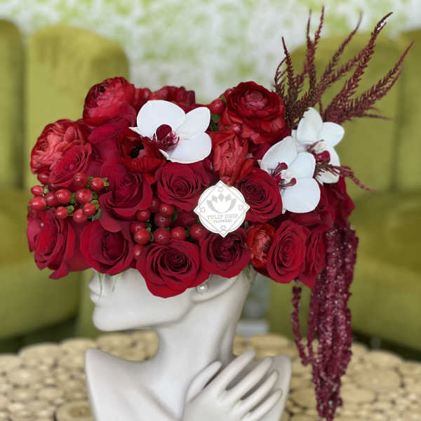 Red rose arrangement with white orchids on a mannequin head vase