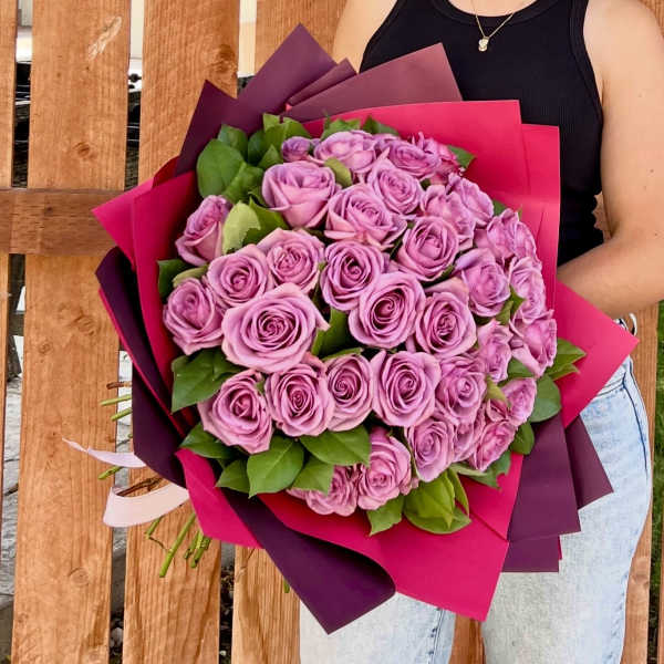 Large bouquet of lavender roses wrapped in bright pink and purple paper