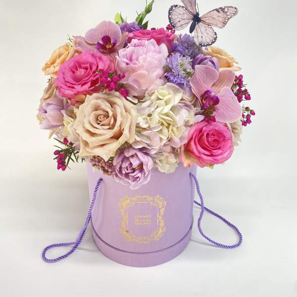 Pink and lavender flower arrangement in a lavender hat box with a butterfly topper