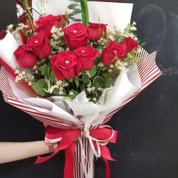 Bouquet of red roses wrapped in striped paper with a red ribbon