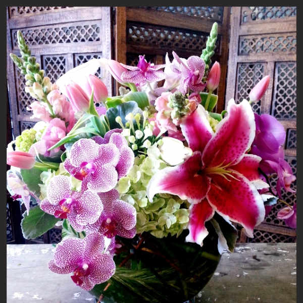 Pink orchids and lilies arranged in a glass vase