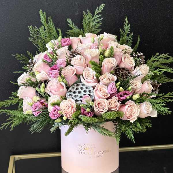 Pink roses and lisianthus in a pale pink hat box with greenery