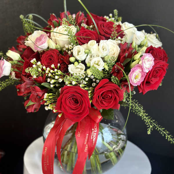 Bouquet of red and white roses in a glass vase with a red ribbon