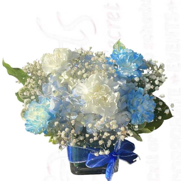 Blue and white flower arrangement in a square glass vase with a blue ribbon