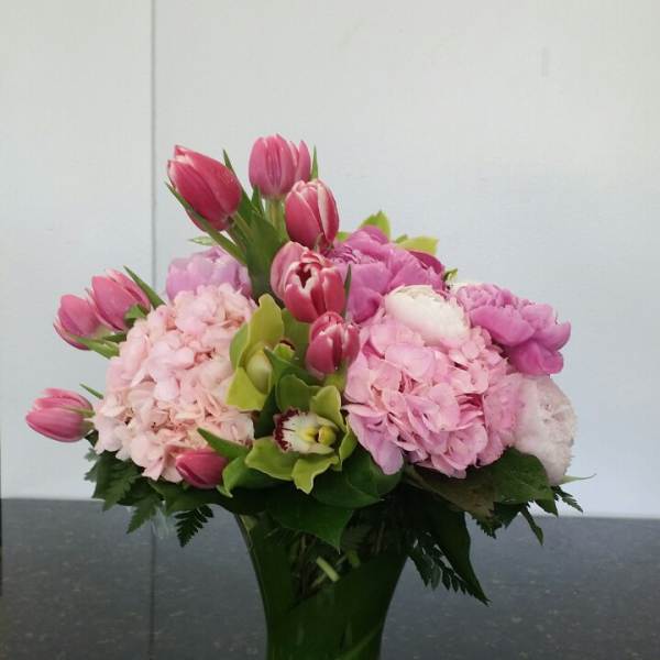 Pink tulips and hydrangeas arranged in a clear glass vase