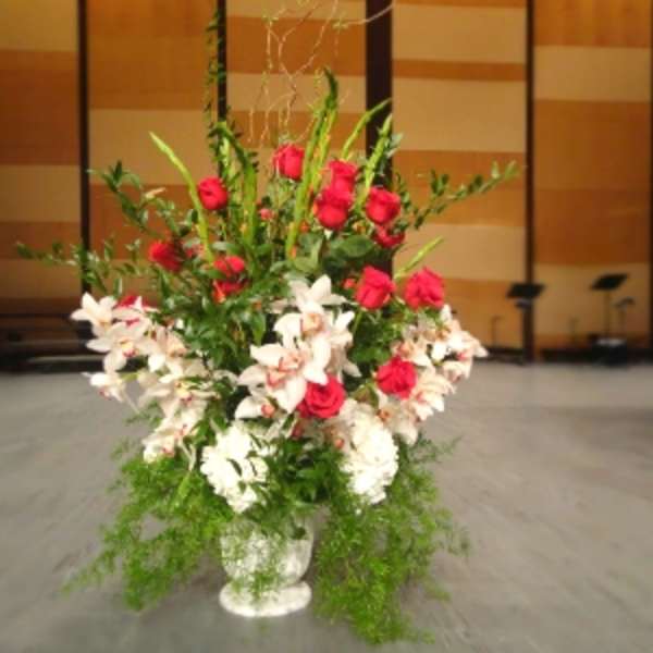 Tall arrangement of red roses and white lilies in a white urn-style vase
