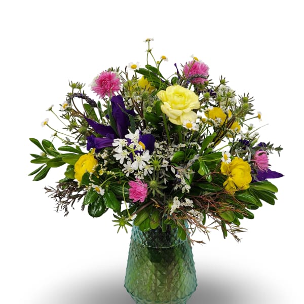 Mixed bouquet of yellow, pink, purple, and white flowers in a green glass vase
