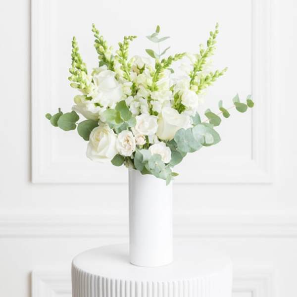 White roses and snapdragons in a tall white vase