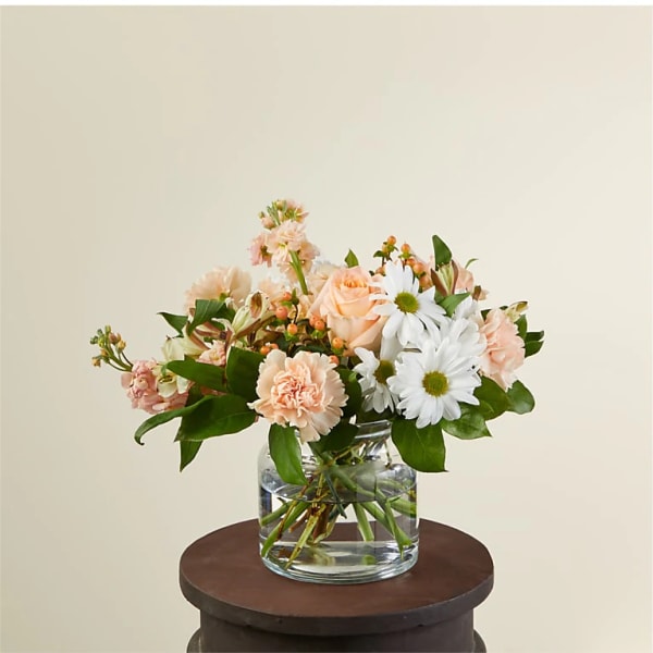 Peach and white flowers arranged in a clear glass vase