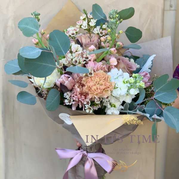 Hand-tied bouquet of pastel flowers with eucalyptus and a lavender ribbon