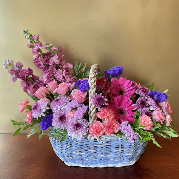 Basket of pink and purple flowers with a woven handle