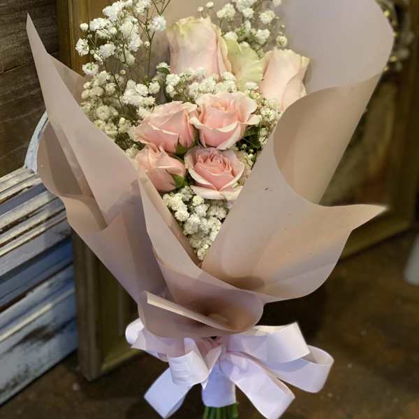Bouquet of pale pink roses with white baby's breath in pink wrapping