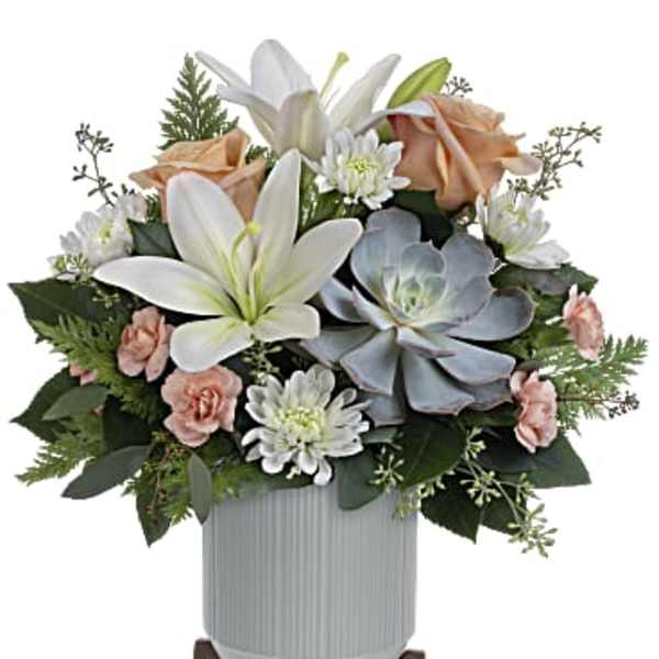 White lilies and peach roses arranged in a vase with daisies and succulents
