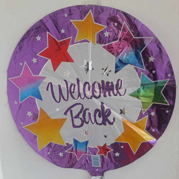 Round purple foil balloon with stars and the words Welcome Back